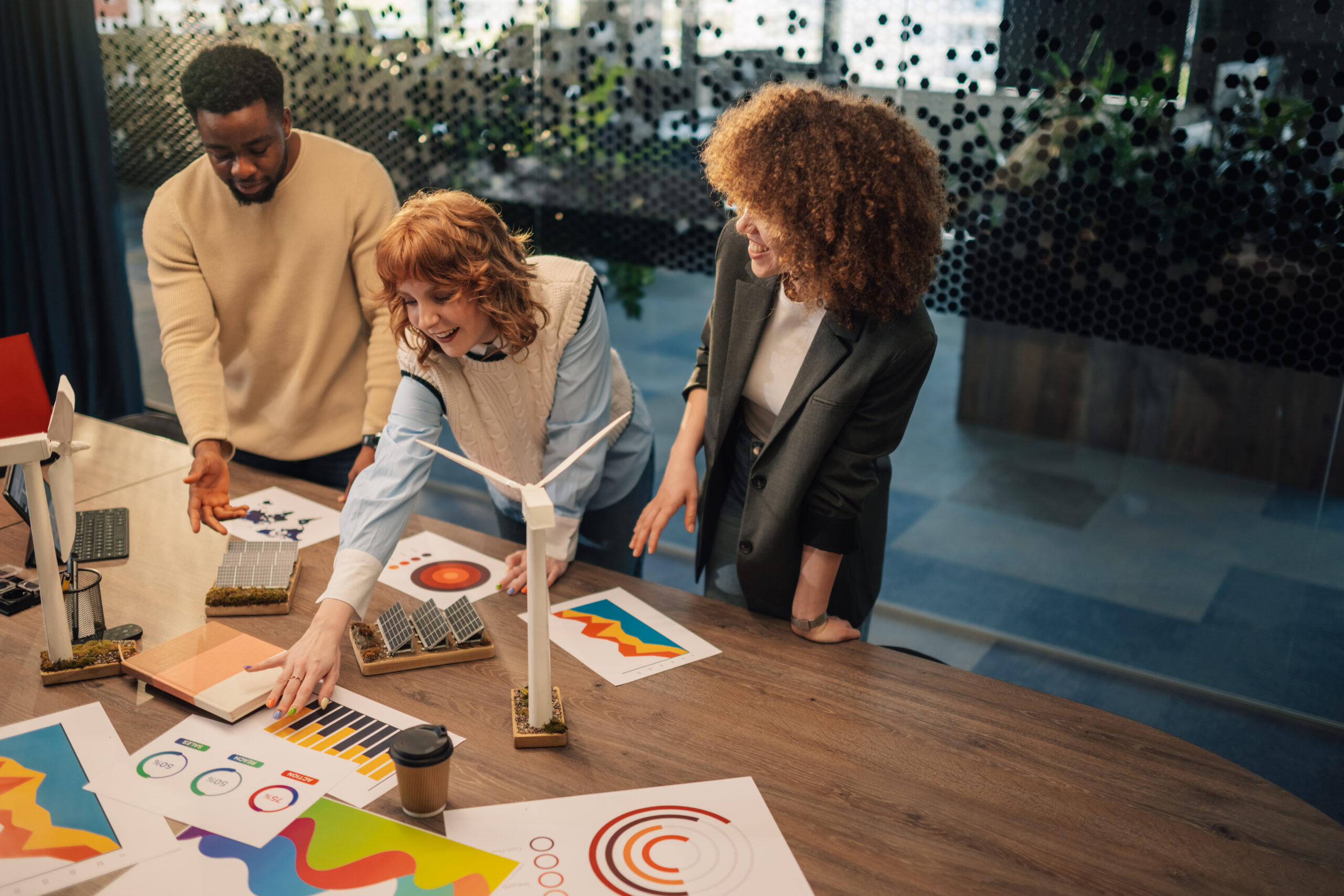 Multicultural businesspeople standing at modern office and working on paperwork and analysis for renewable energy resources technology. Diverse environmentalists developing clean energy technology.